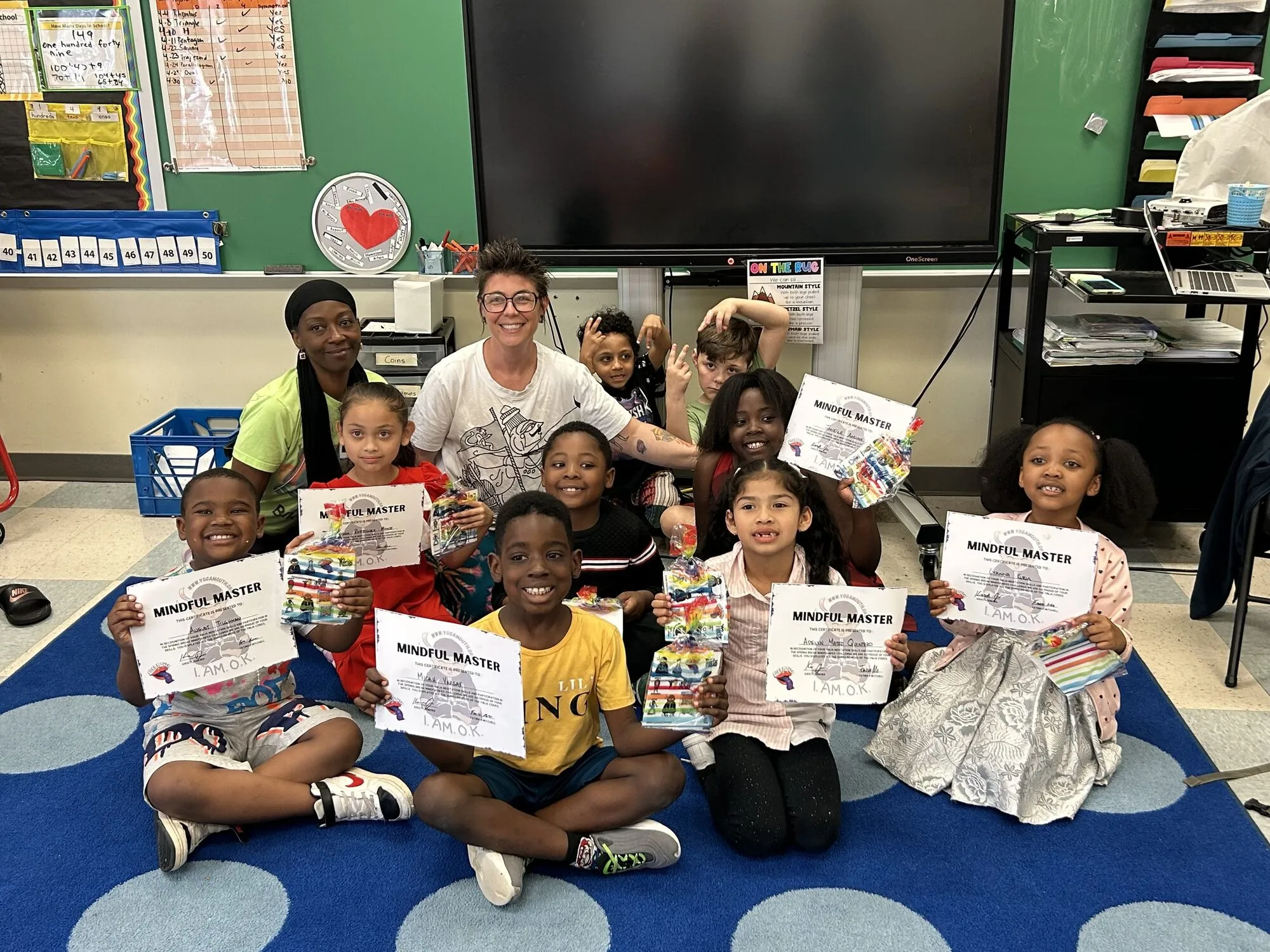 Children in a classroom holding up hand-made signs during a Yoga Mouth session
