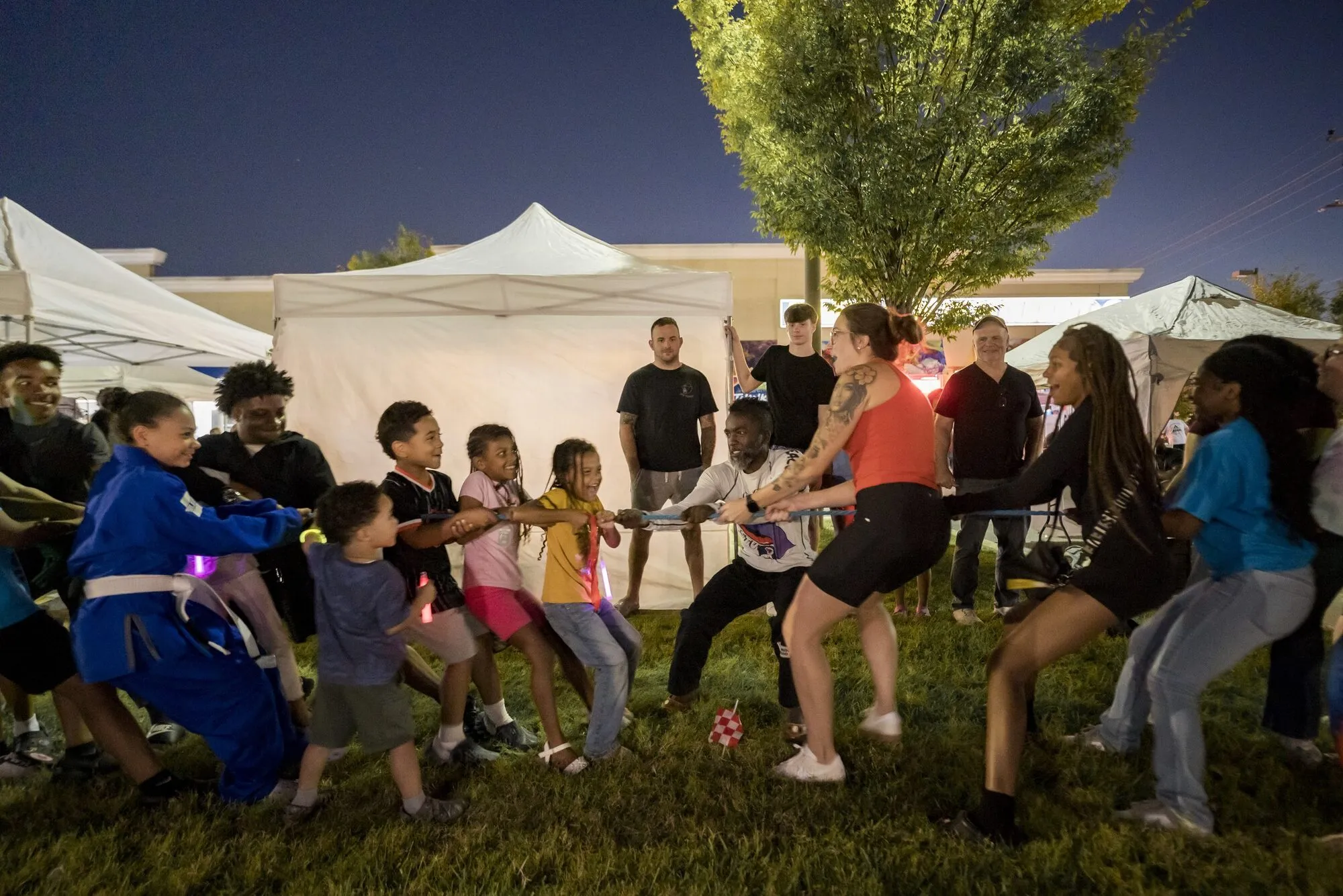 Families and children playing tug of war at an outdoor community event
