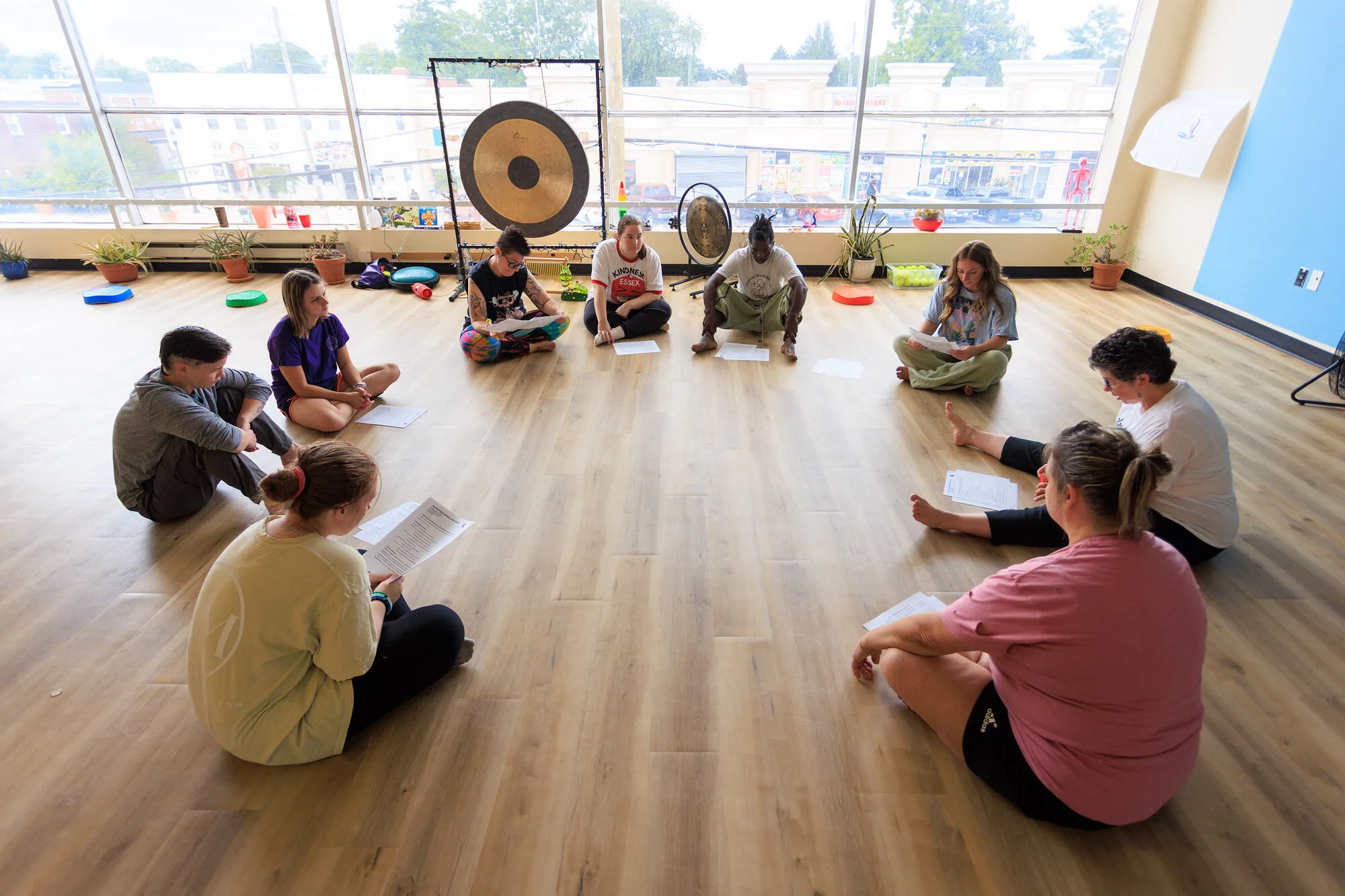 Educators sitting in a circle on the studio floor with handouts, working through a session together