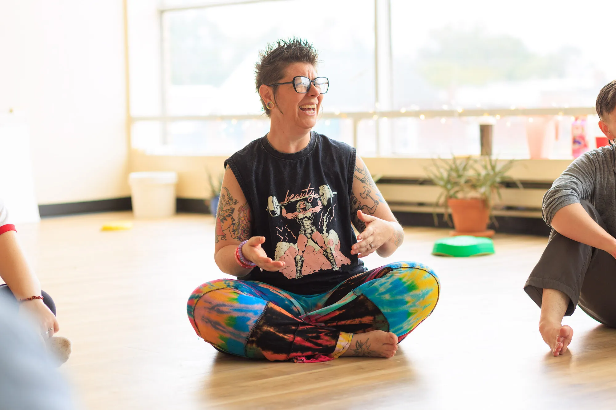An educator sitting cross-legged on the studio floor, laughing mid-conversation during a session