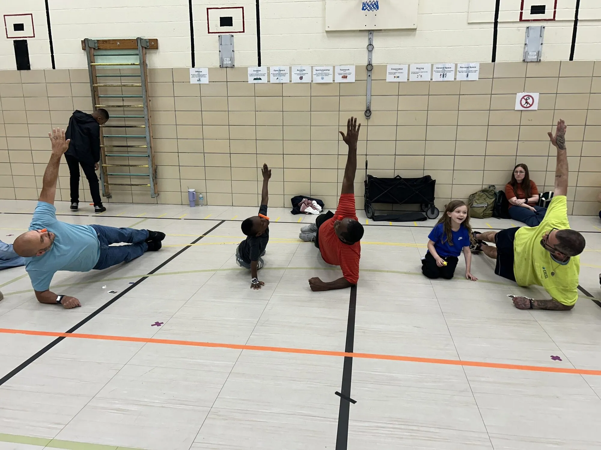 Children and adults sitting in a circle during a Yoga Mouth session in a school gym