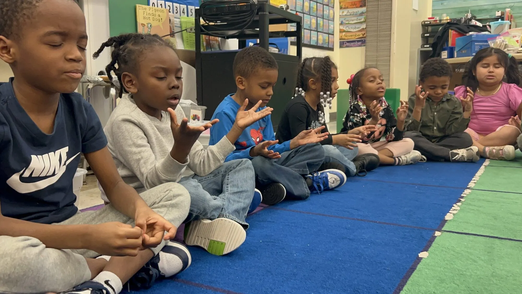 Students seated on a school floor during a Yoga Mouth session